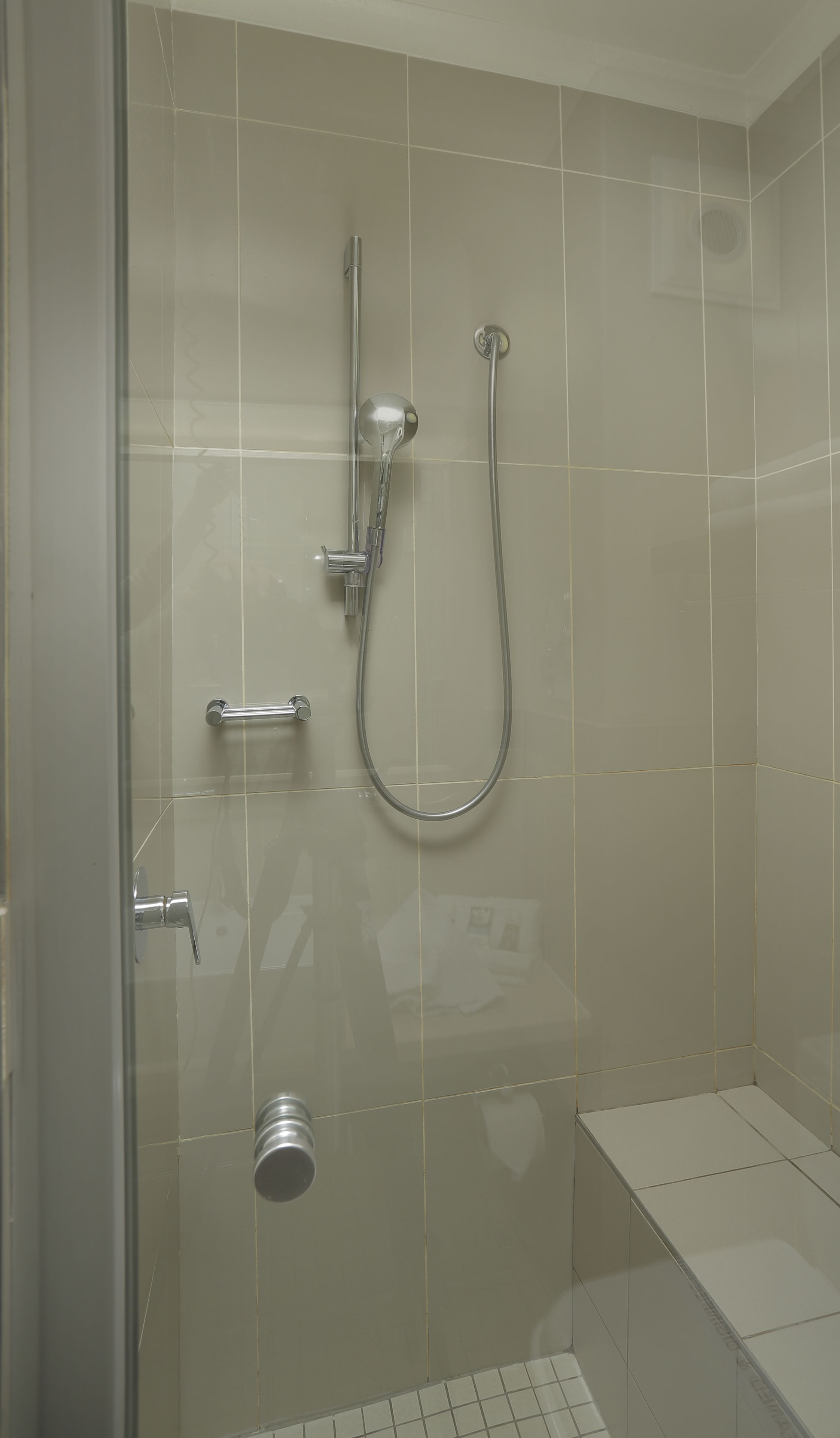 Eine Dusche mit Handbrause und am Wand montiertem Wasserhahn.