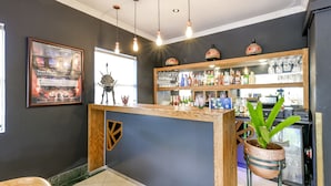 A bar area with a wooden counter, a potted plant, and a refrigerator.