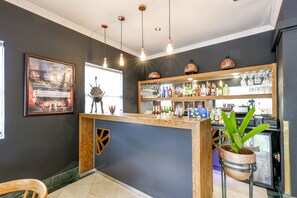 A bar area with a wooden counter, a potted plant, and a refrigerator.