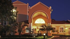 A hotel with a large arched entrance, palm trees, and a fountain in the courtyard.