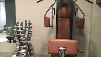 Ett gym med ett brett utbud av träningsredskap, inklusive hantlar och en bänkpress.