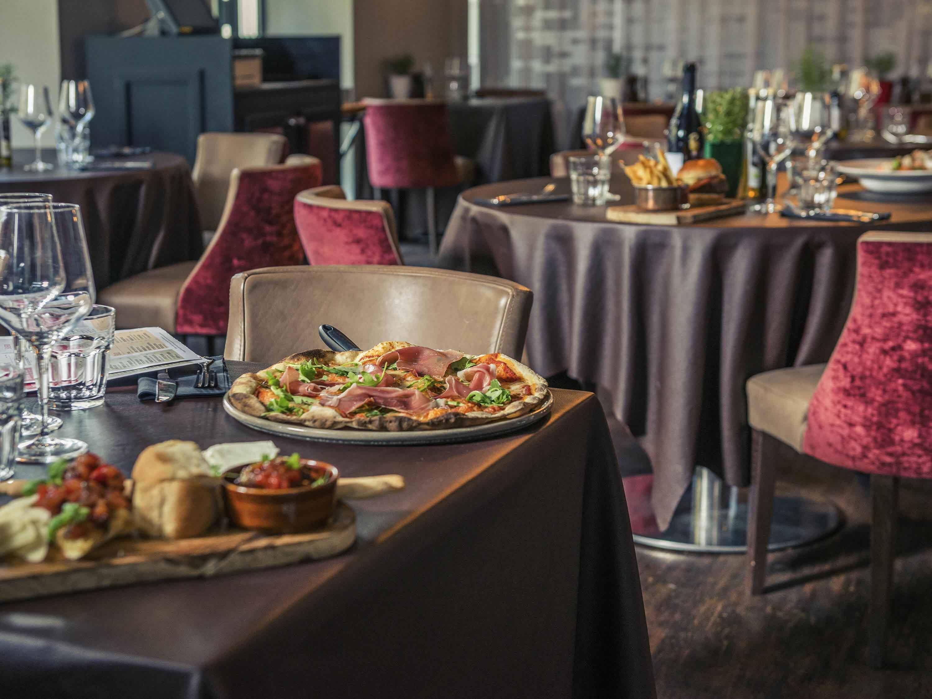 Ein Restaurant mit Pizza auf dem Tisch, Weingläsern und verschiedenen Speisen.