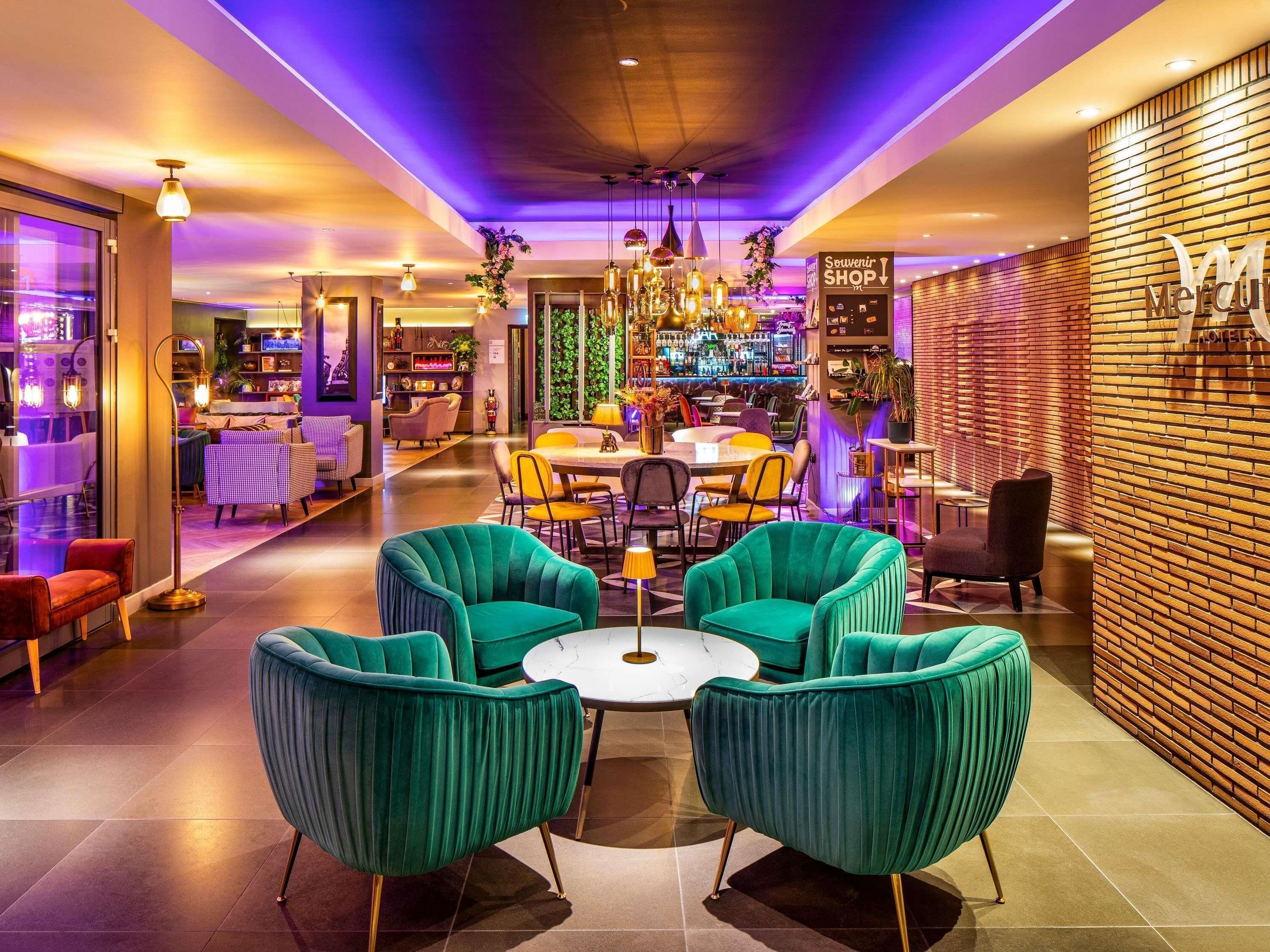 A hotel lobby with teal armchairs, a bar area, and a sign for the souvenir shop.