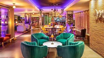 A hotel lobby with teal armchairs, a bar area, and a sign for the souvenir shop.
