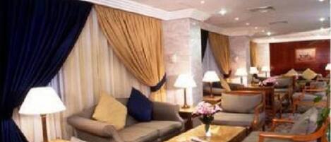 Eine Hotlellobby mit einer Couch, Sesseln, einem Couchtisch und Lampen.