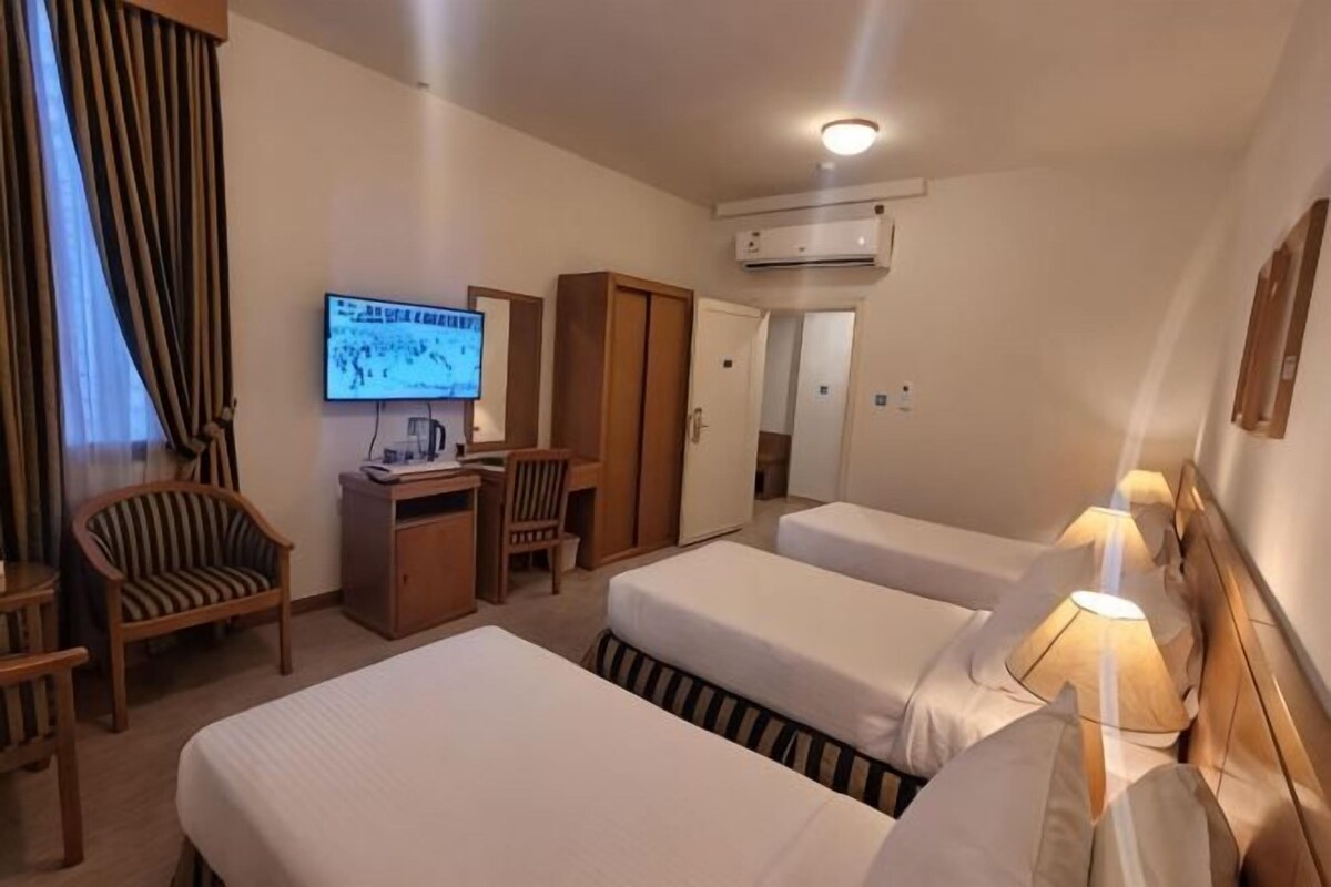 Habitación de hotel con dos camas, un escritorio, un televisor y un equipo de aire acondicionado.