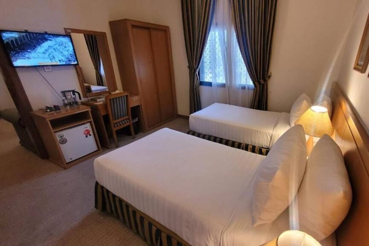 A hotel room with two beds, a TV, a desk, and a wardrobe.