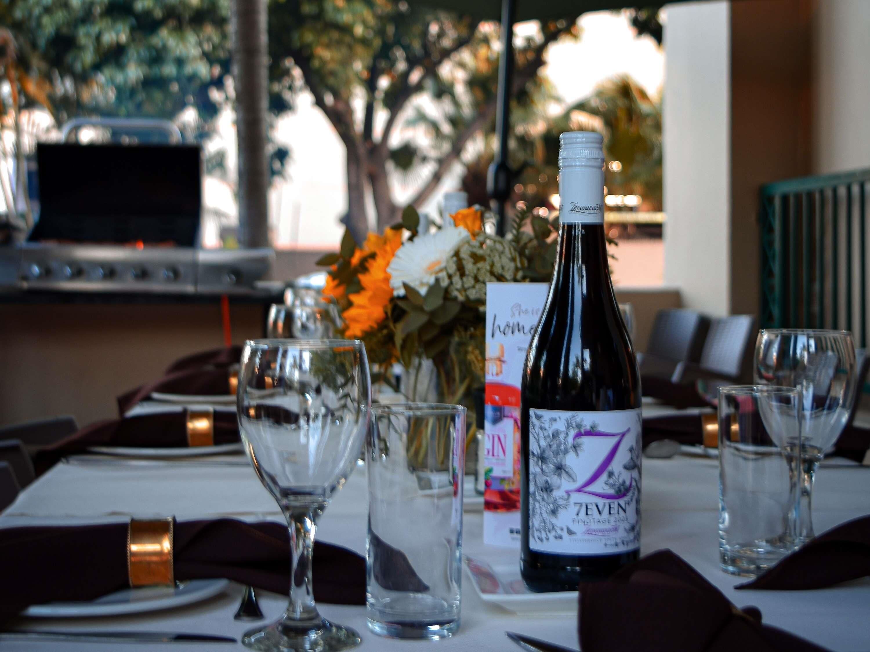 A table set for dining with a bottle of wine, glasses, and a menu.