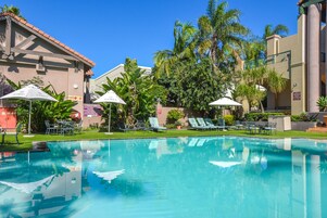 Una piscina al aire libre, sombrillas, sillones reclinables de piscina