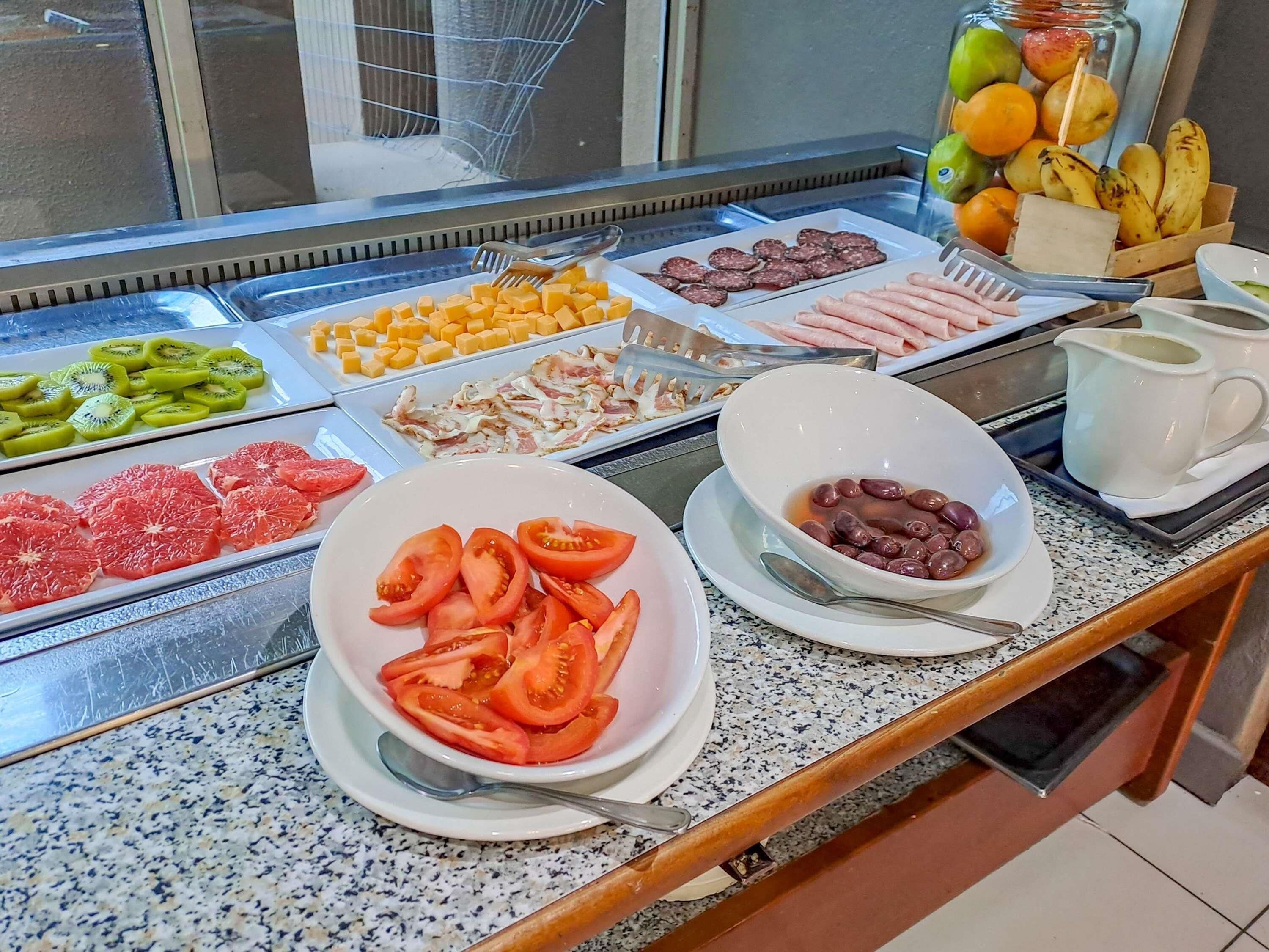 A buffet with various food items including sliced fruits, meats, and cheeses.