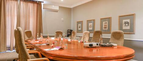 A conference room with a large oval table, six chairs, a projector, and framed pictures on the wall.