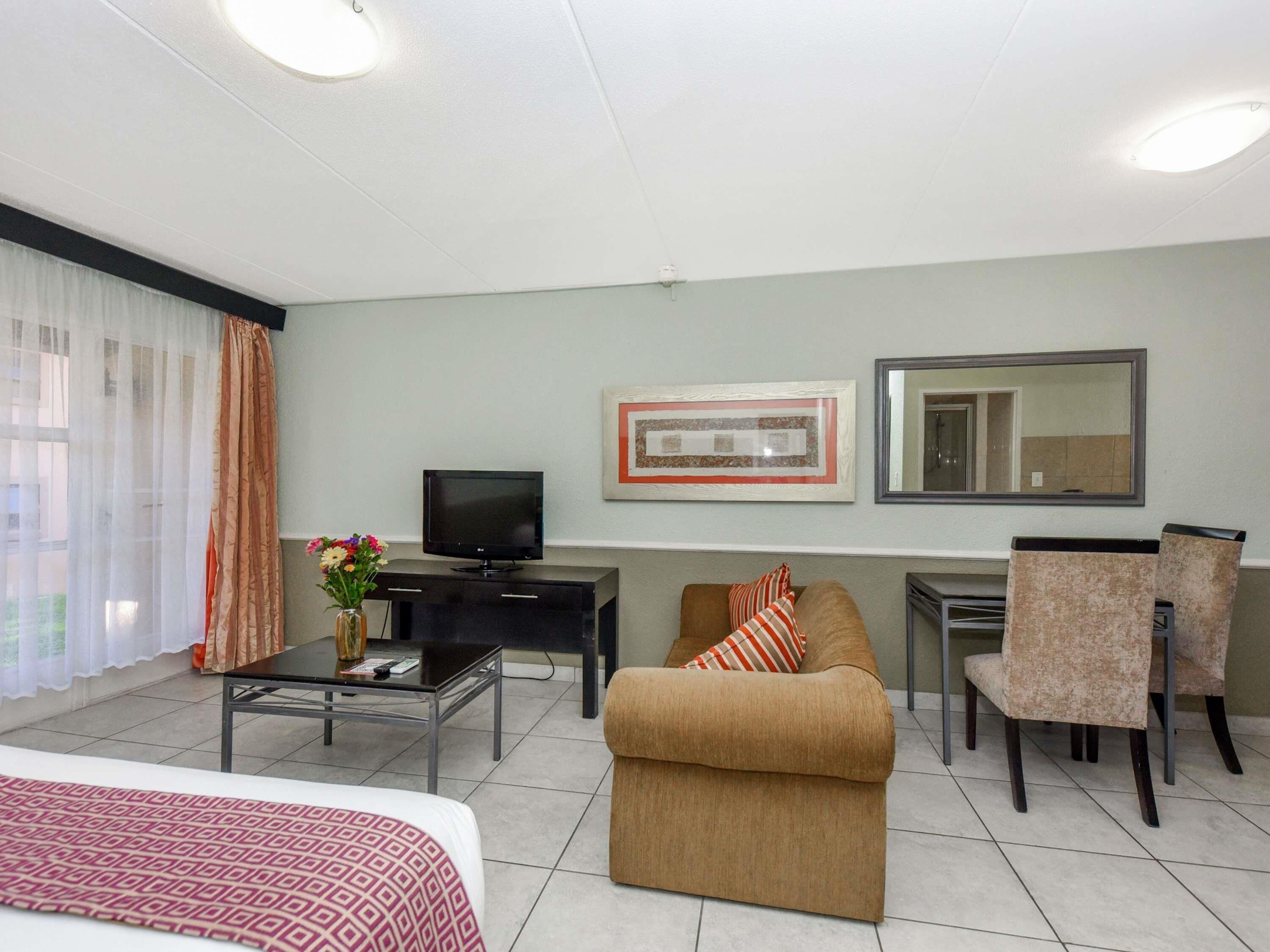 Ein Hotelzimmer mit einem Bett, einem Sofa, einem Fernseher, einem Schreibtisch und einem Sessel.
