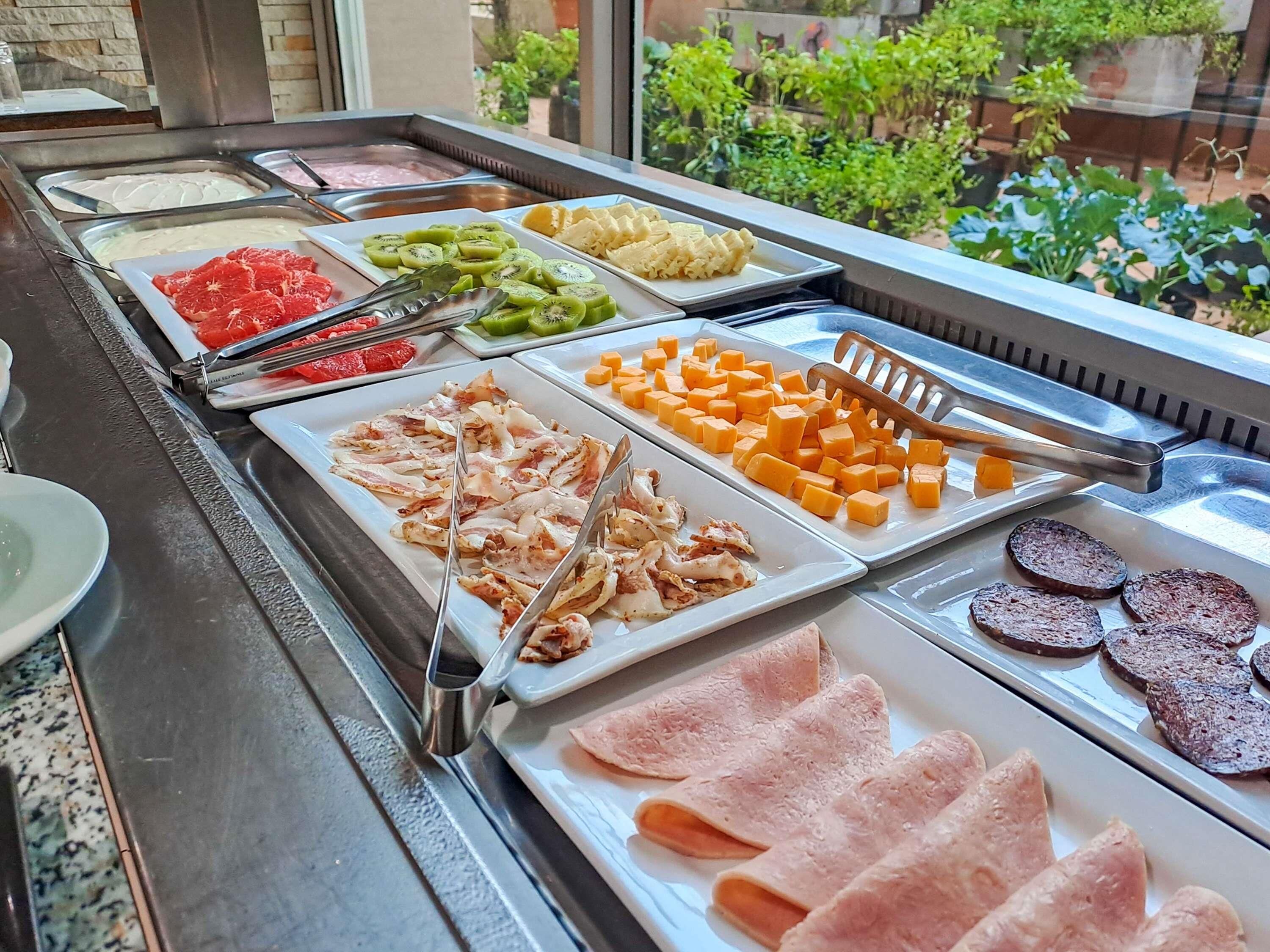 Un bufé con diversas opciones de comida, incluyendo carnes, quesos y frutas.