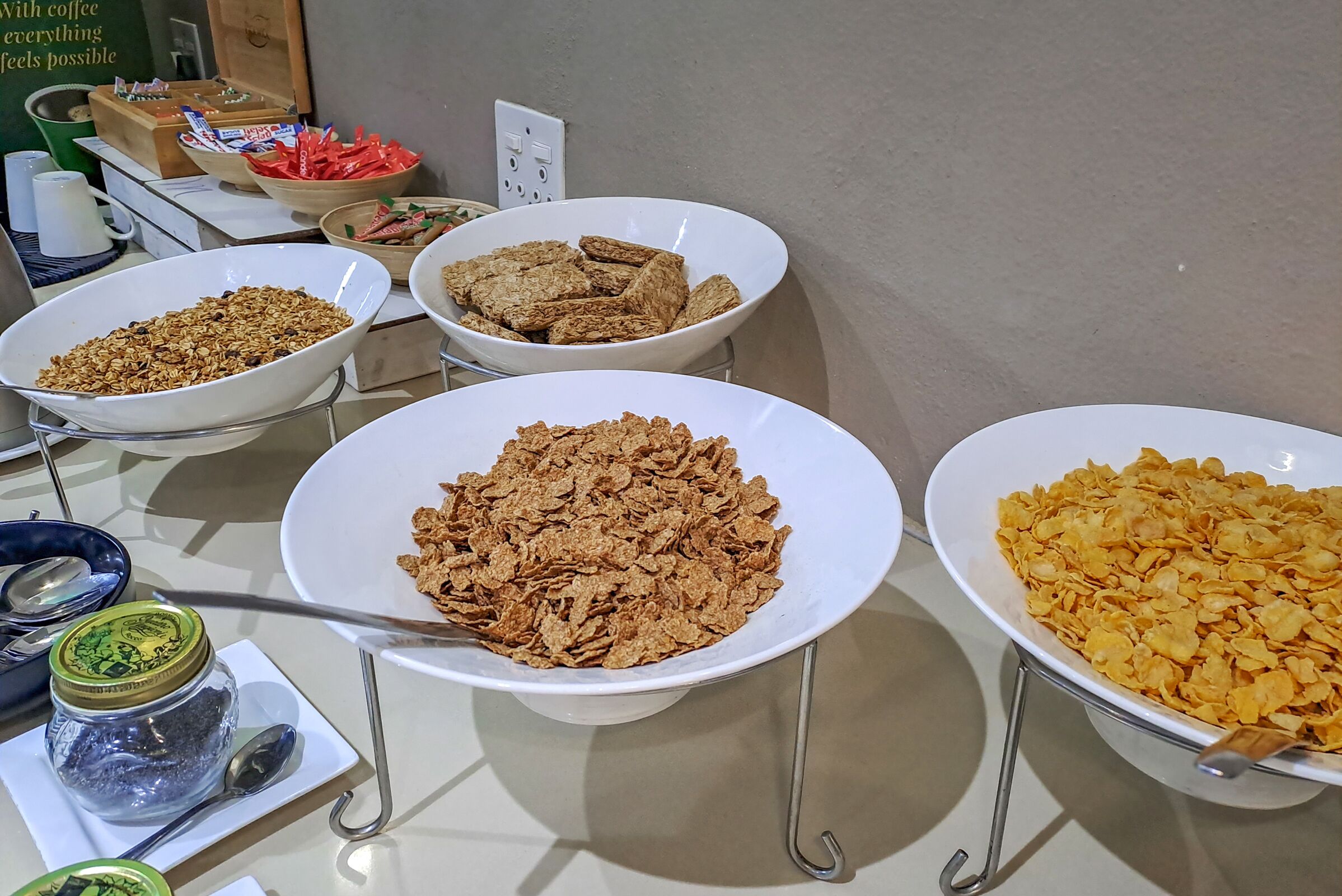 A buffet table with various food items including cereal, granola, and cookies.