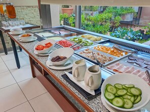 A buffet with various food options, a coffee station, and a view of the garden through the window. - Mercure Nelspruit Hotel (Mbombela)