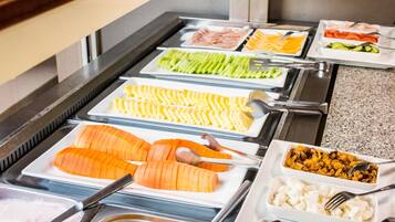 A buffet with various food items including sliced salmon, cheese, vegetables, and fruits.