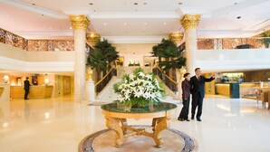 Un hall de hotel con una recepción, una escalera y una mesa decorada con flores.