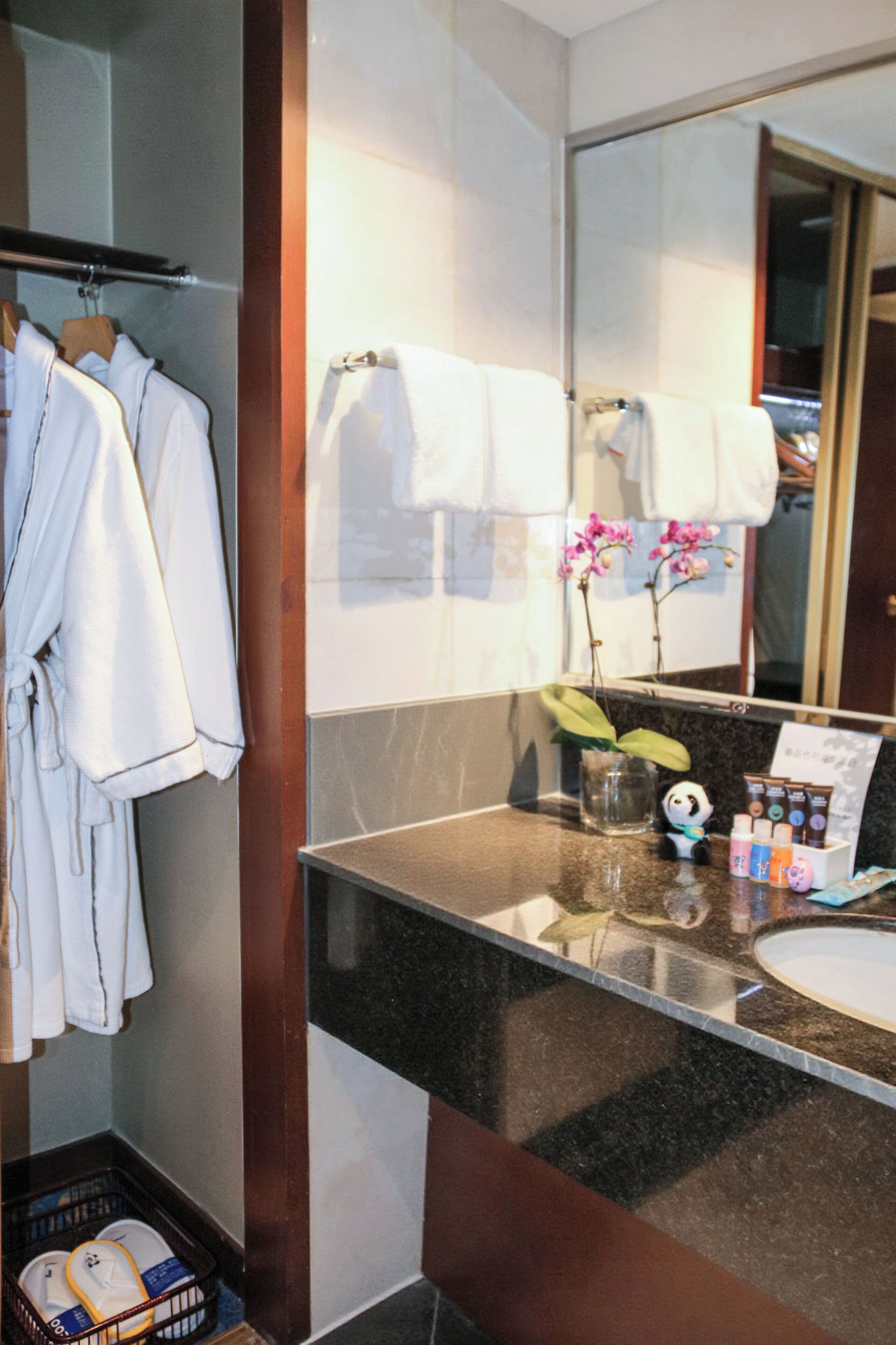 A bathroom with a sink, mirror, and towel rack. There are towels hanging on the rack and a small plant on the counter.