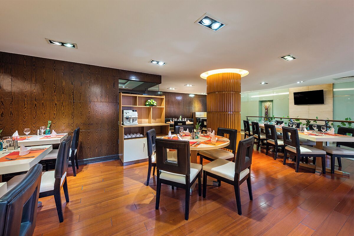 A restaurant with wooden flooring, multiple dining tables, and chairs.