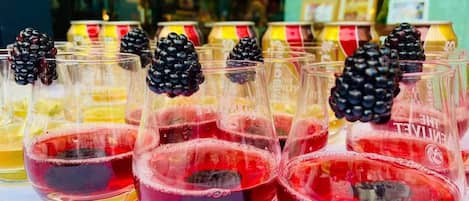 Multiple glasses of red beverage with blackberries, displayed on a table.