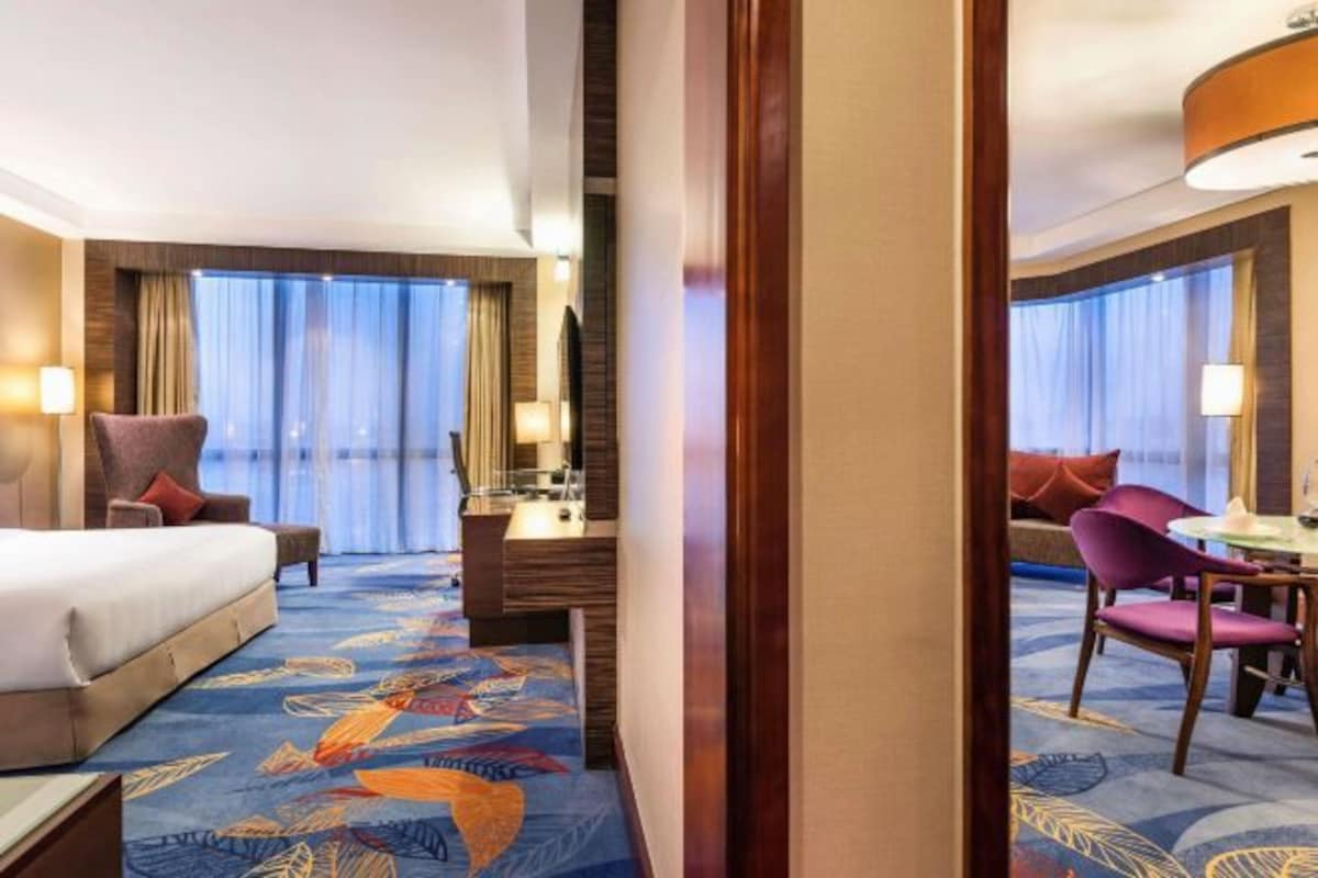 A hotel room with a bed, a desk, a chair, and a view of the outside.