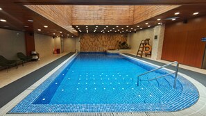 An indoor swimming pool with a wooden ceiling, tiled floor, and a lifebuoy on the wall. - Peace Hotel Beijing (Beijing)