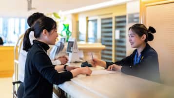 A reception desk with a counter, a digital screen, and a cash register.