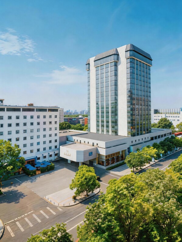 A modern building with a prominent glass facade, a flat-roofed structure, and a courtyard with trees. - Peace Hotel Beijing (Beijing)