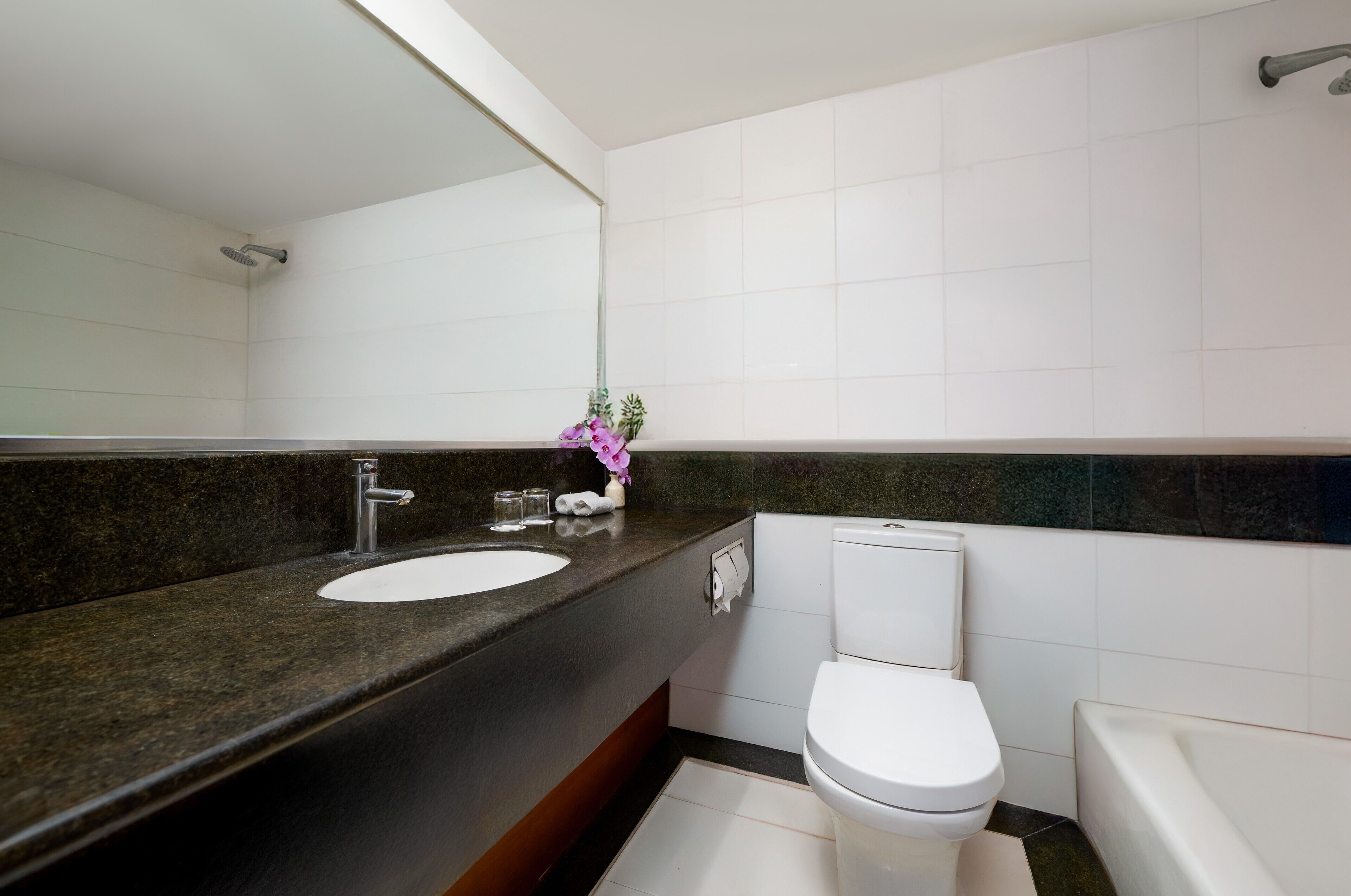A modern bathroom with a granite countertop, white sink, and toilet.