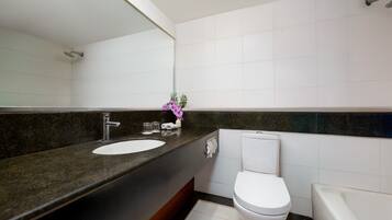 A modern bathroom with a granite countertop, white sink, and toilet.