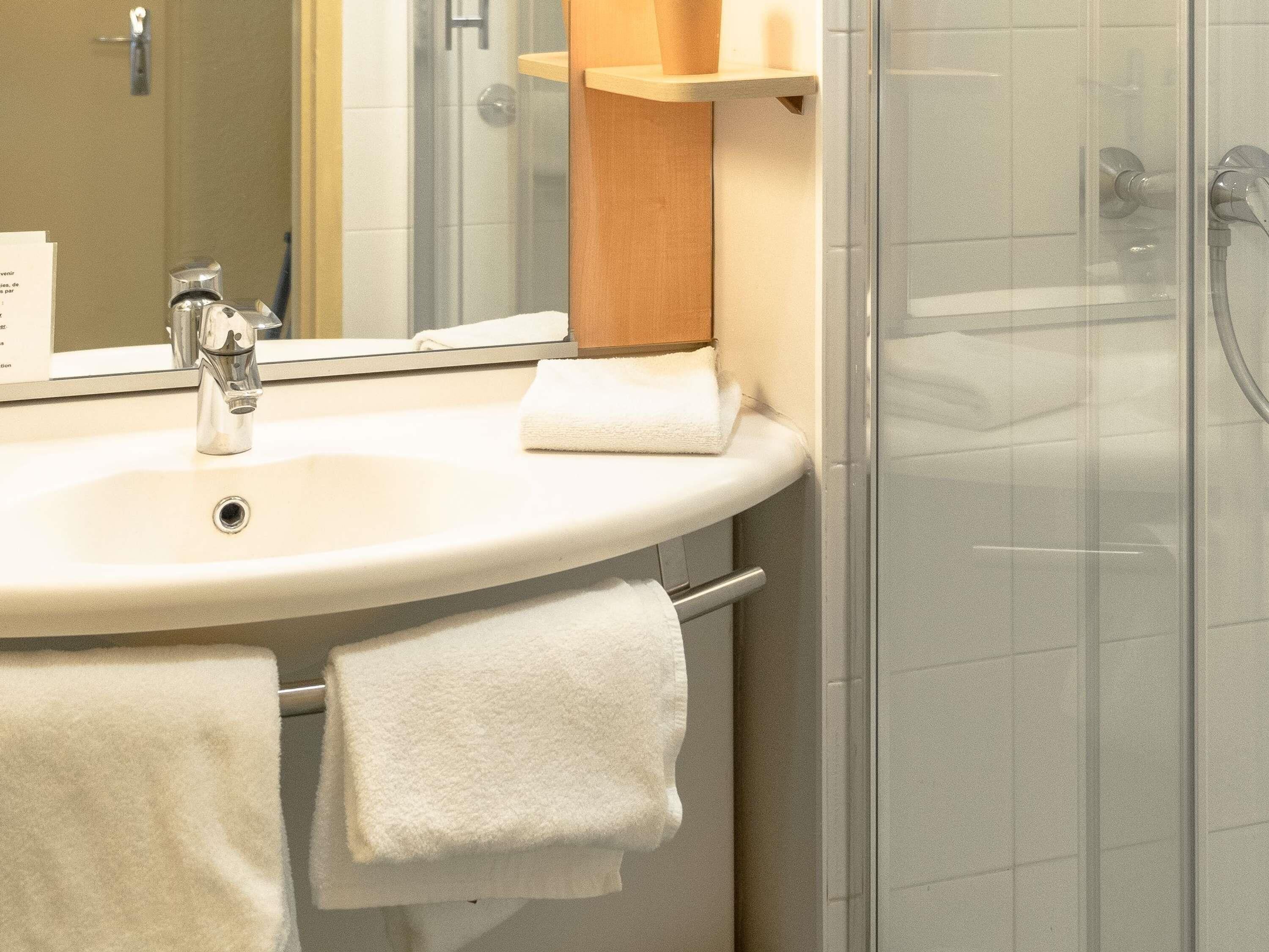 A bathroom with a sink, mirror, and towel rack.