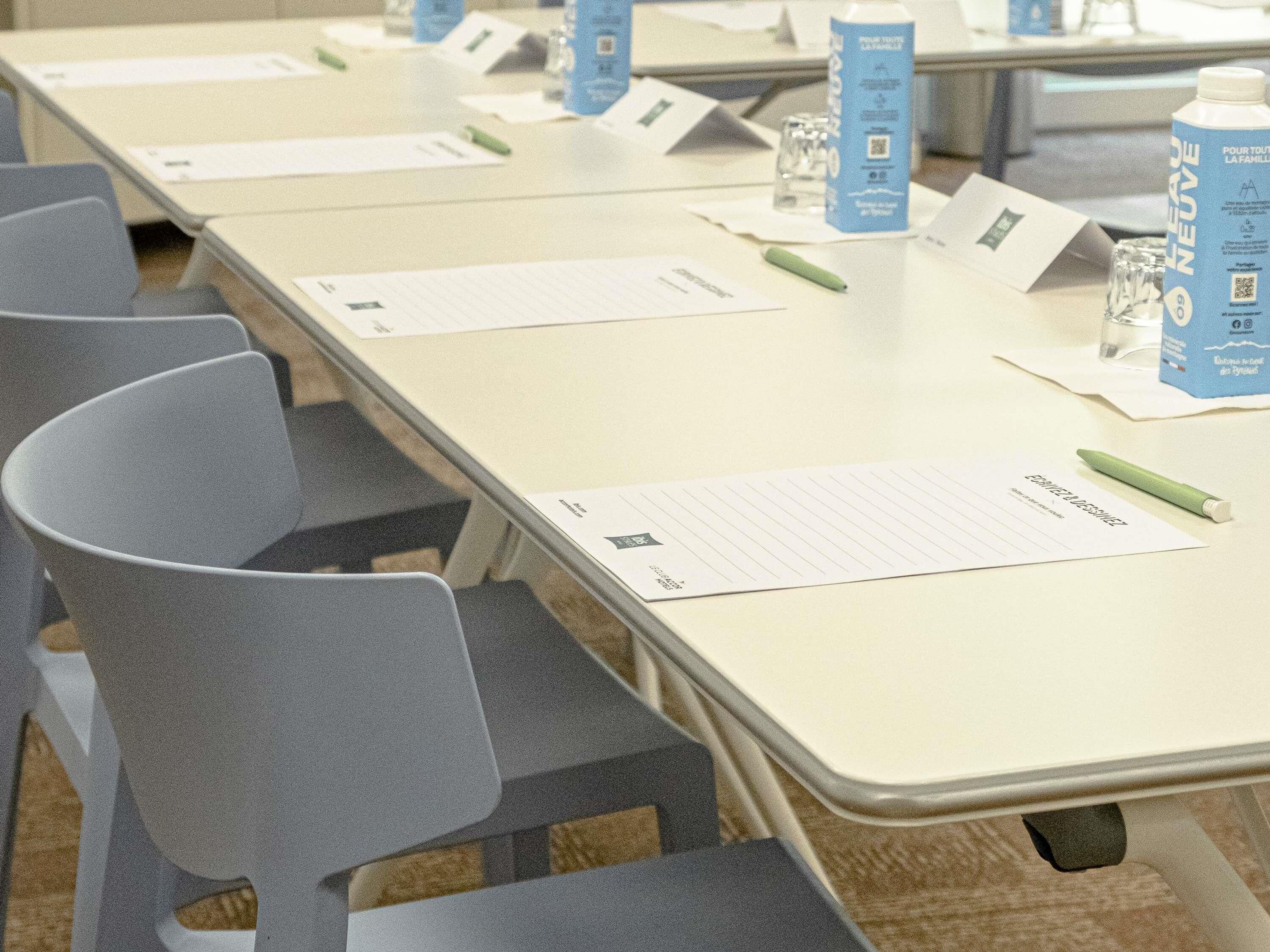 A conference room with tables, chairs, name tags, water bottles, and pens.
