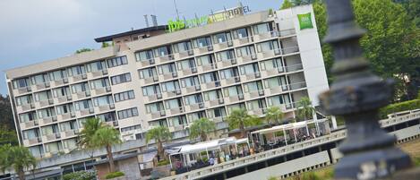A multi-story hotel with a modern design, featuring balconies and a rooftop terrace.