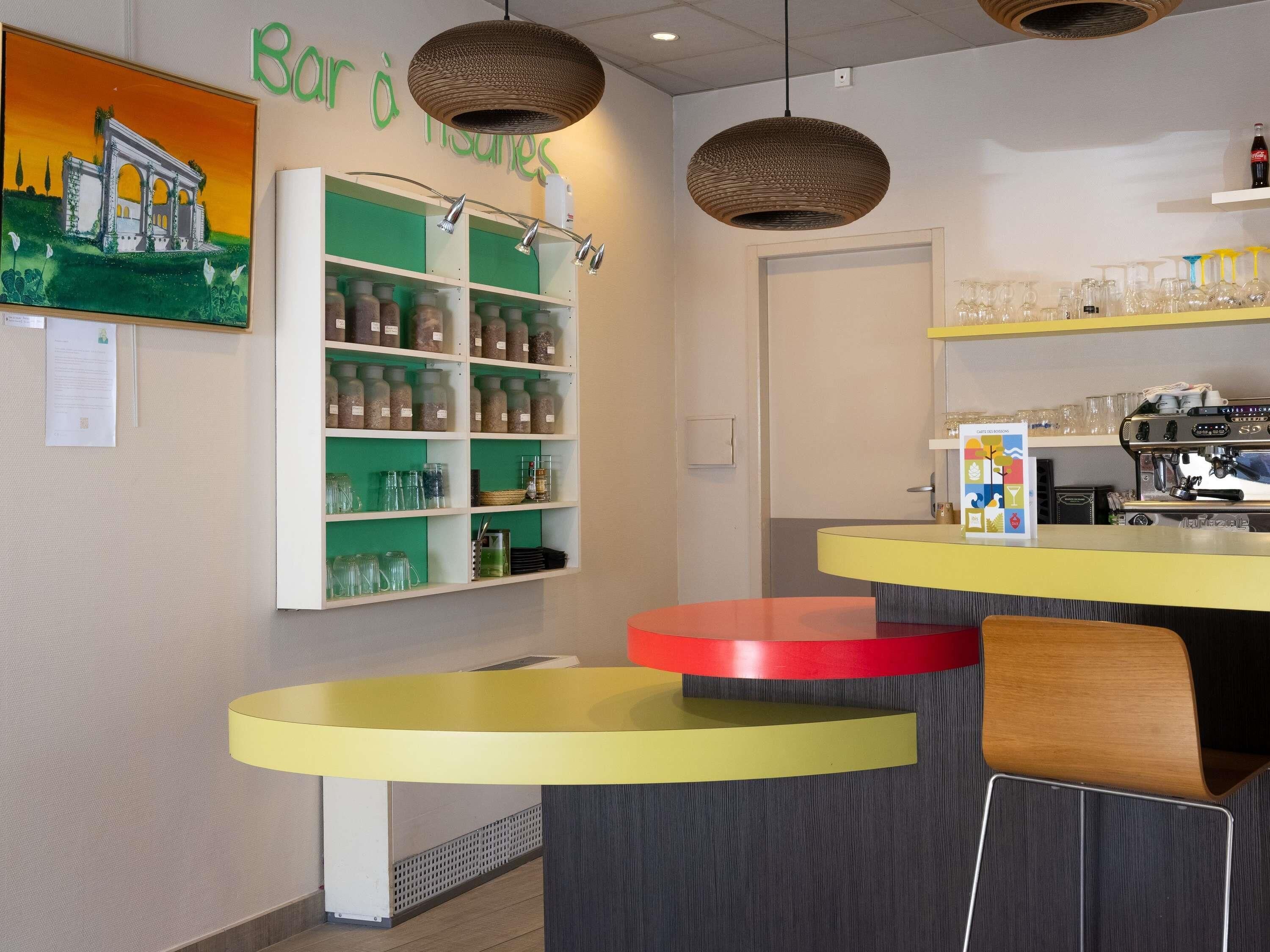 A cafe with a counter, shelves with jars, and a painting on the wall.