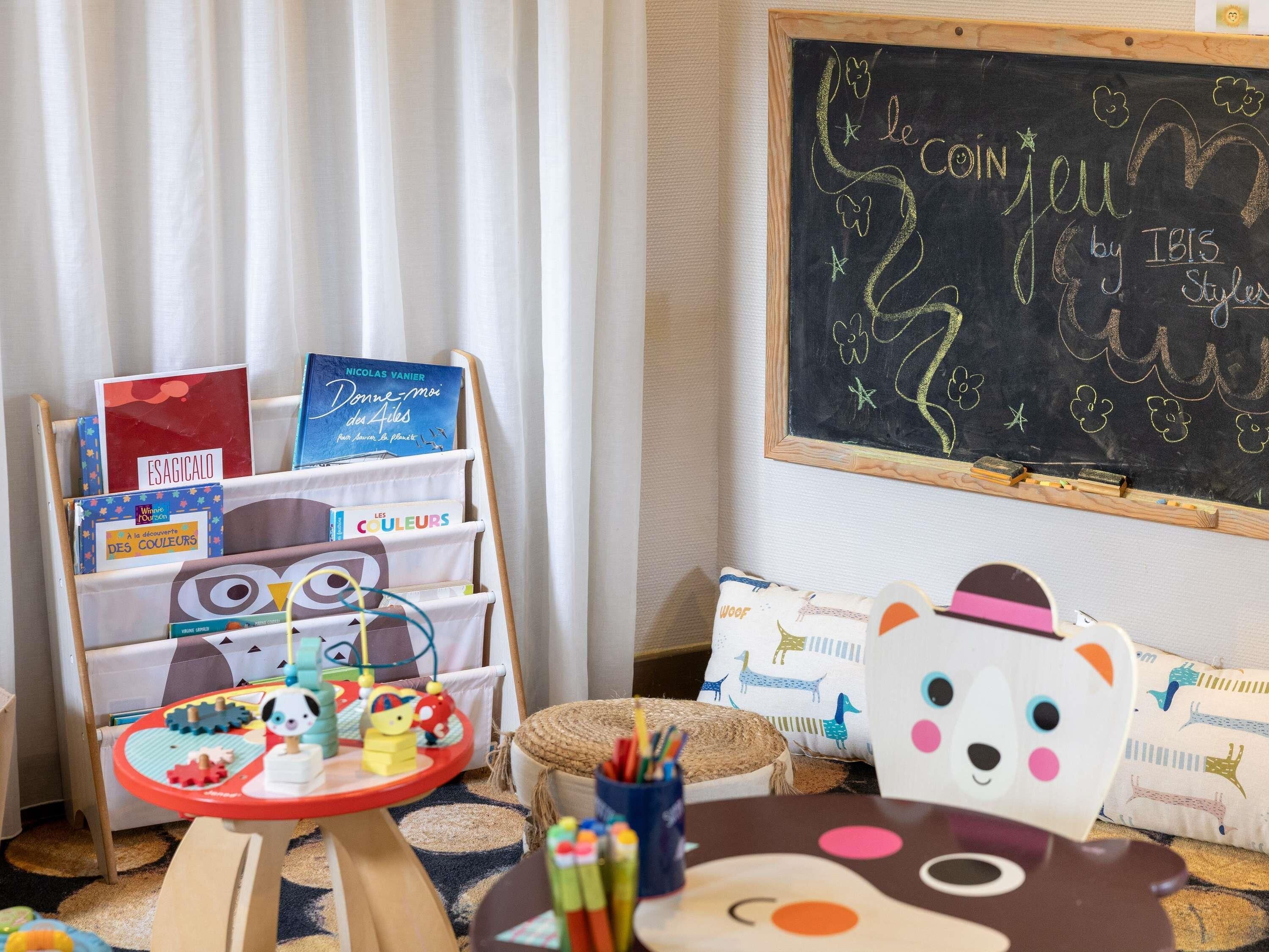 A child's play area with a bookshelf, a chalkboard, and a toy table.