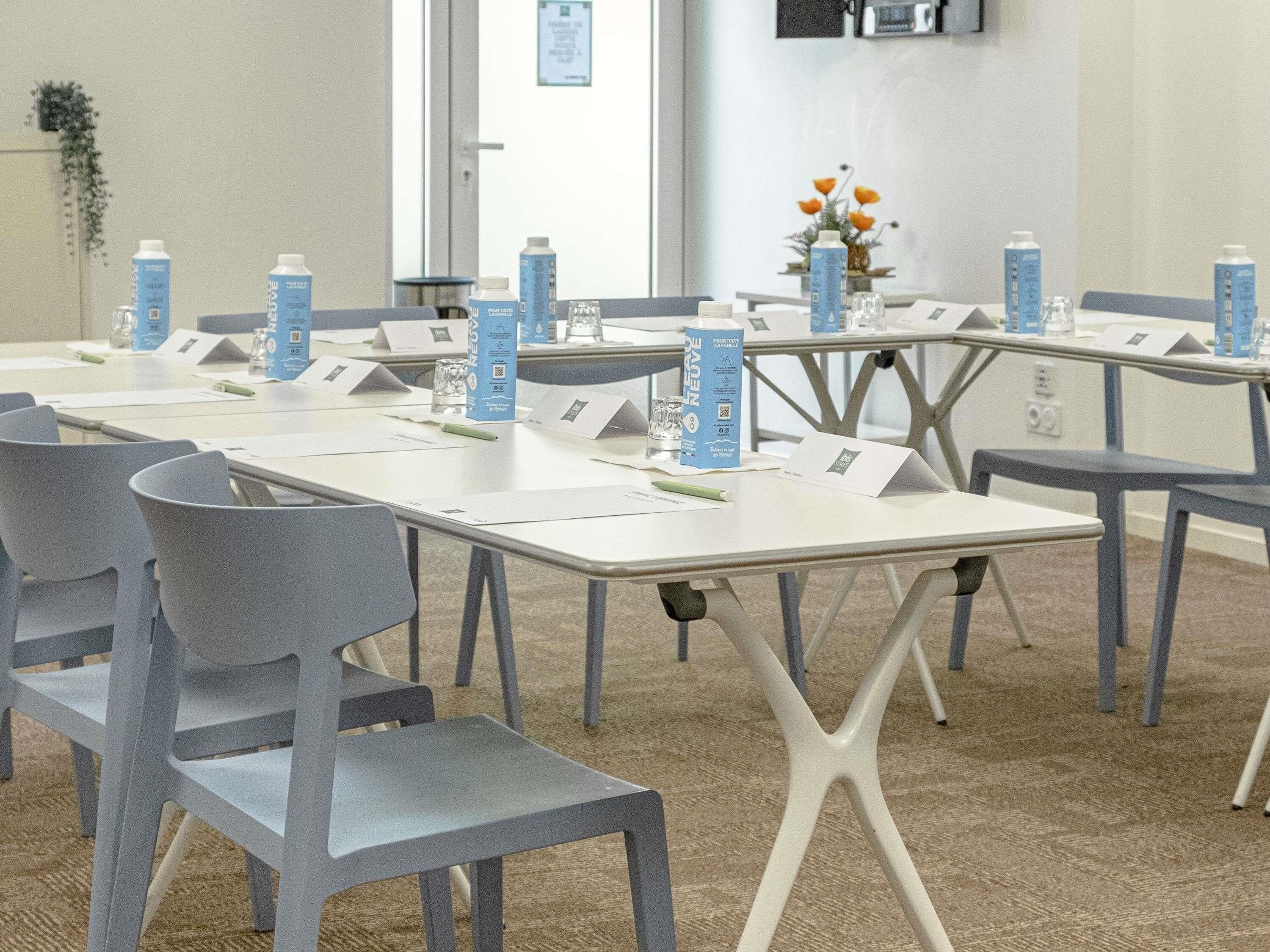 A conference room with tables, chairs, water bottles, and name cards.
