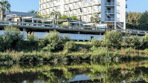 Un hotel de varios pisos con un diseño arquitectónico moderno, que cuenta con balcones y un cuerpo de agua reflectante al frente.