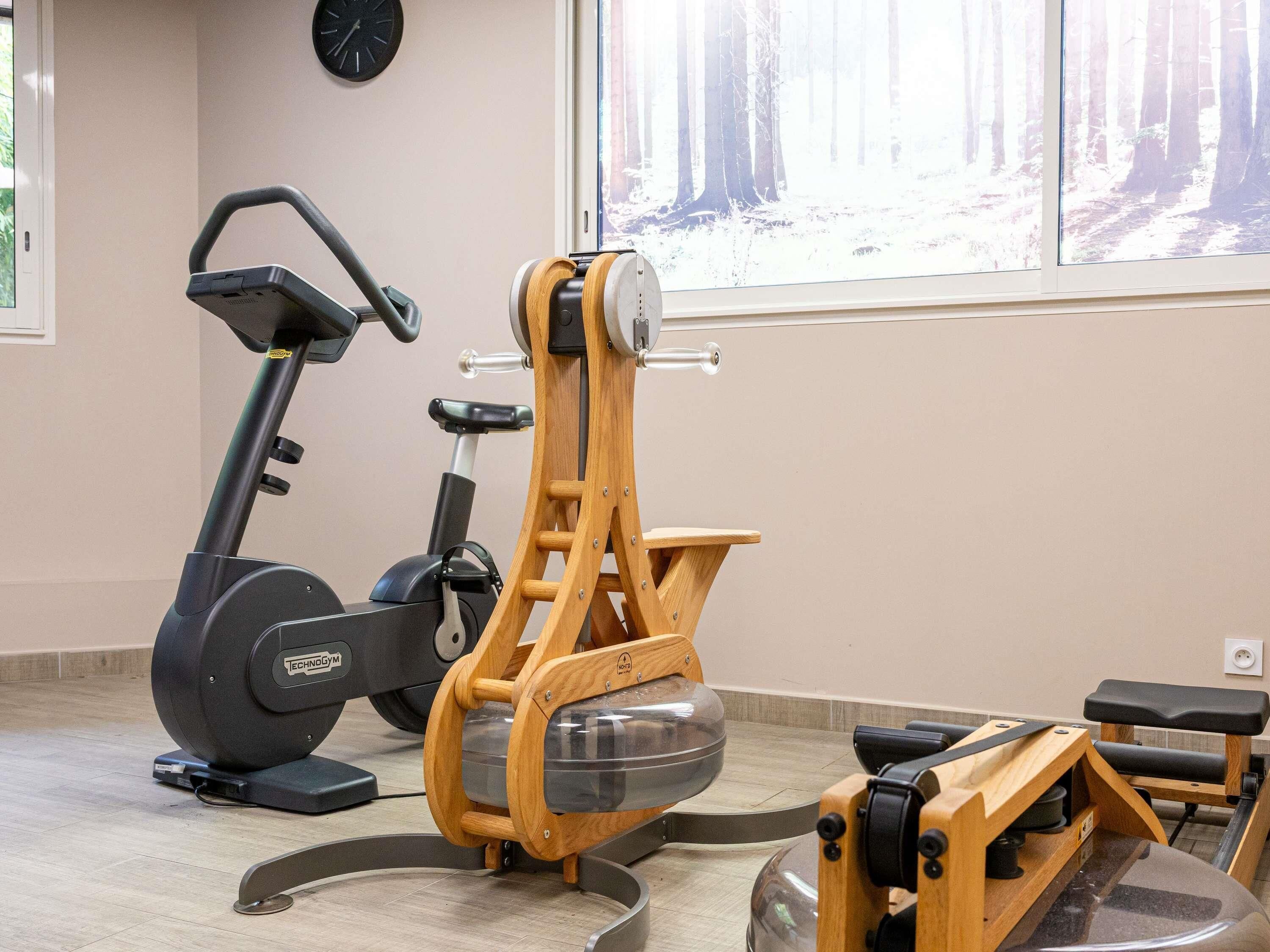 Un gimnasio con una bicicleta estática, una bicicleta elíptica y una máquina de remo.