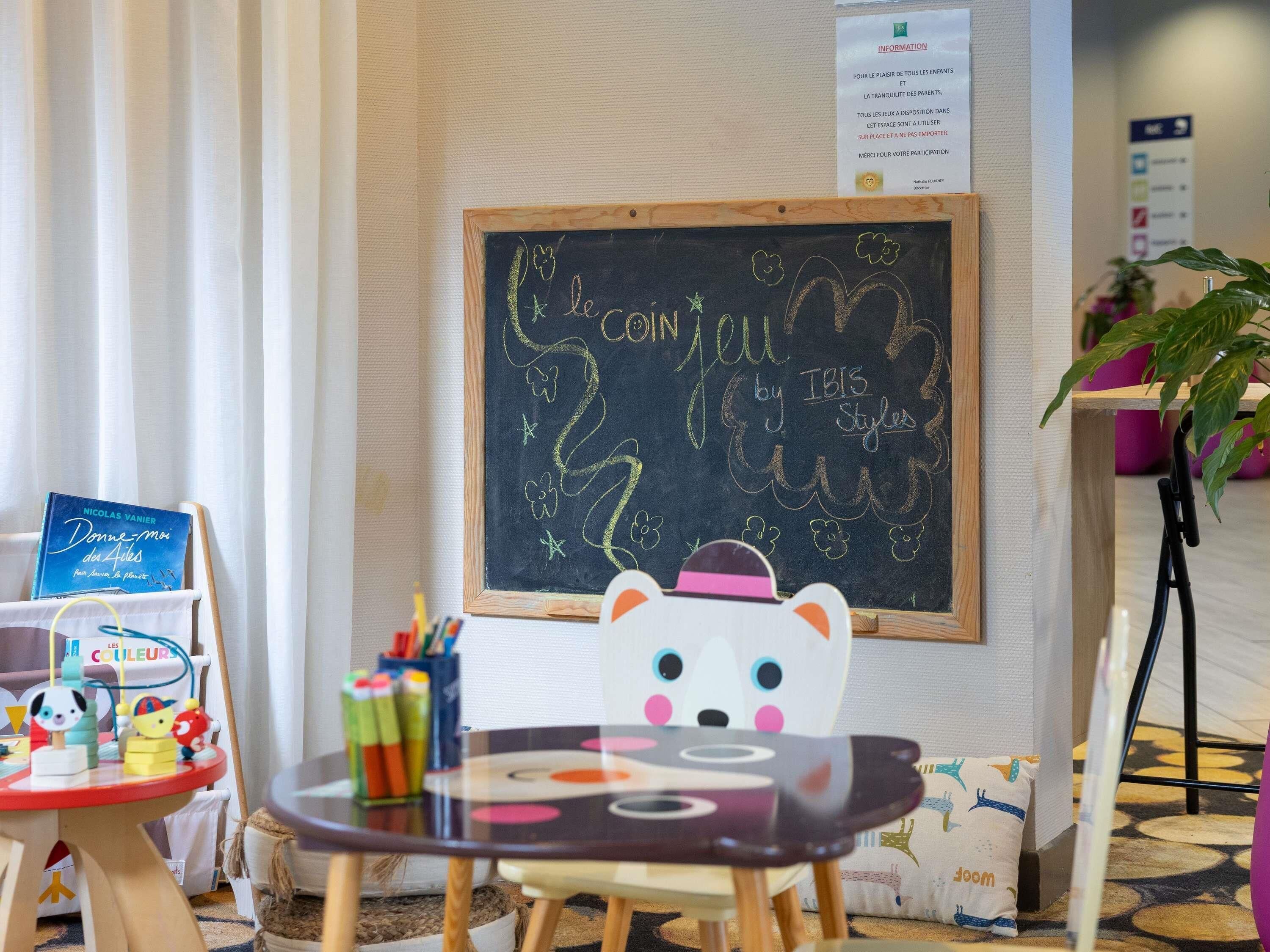Zona de juegos para niños con una pizarra, juguetes y una mesa.