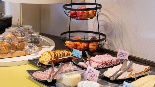 Un bufé con diversos alimentos, incluyendo carnes, quesos y frutas.