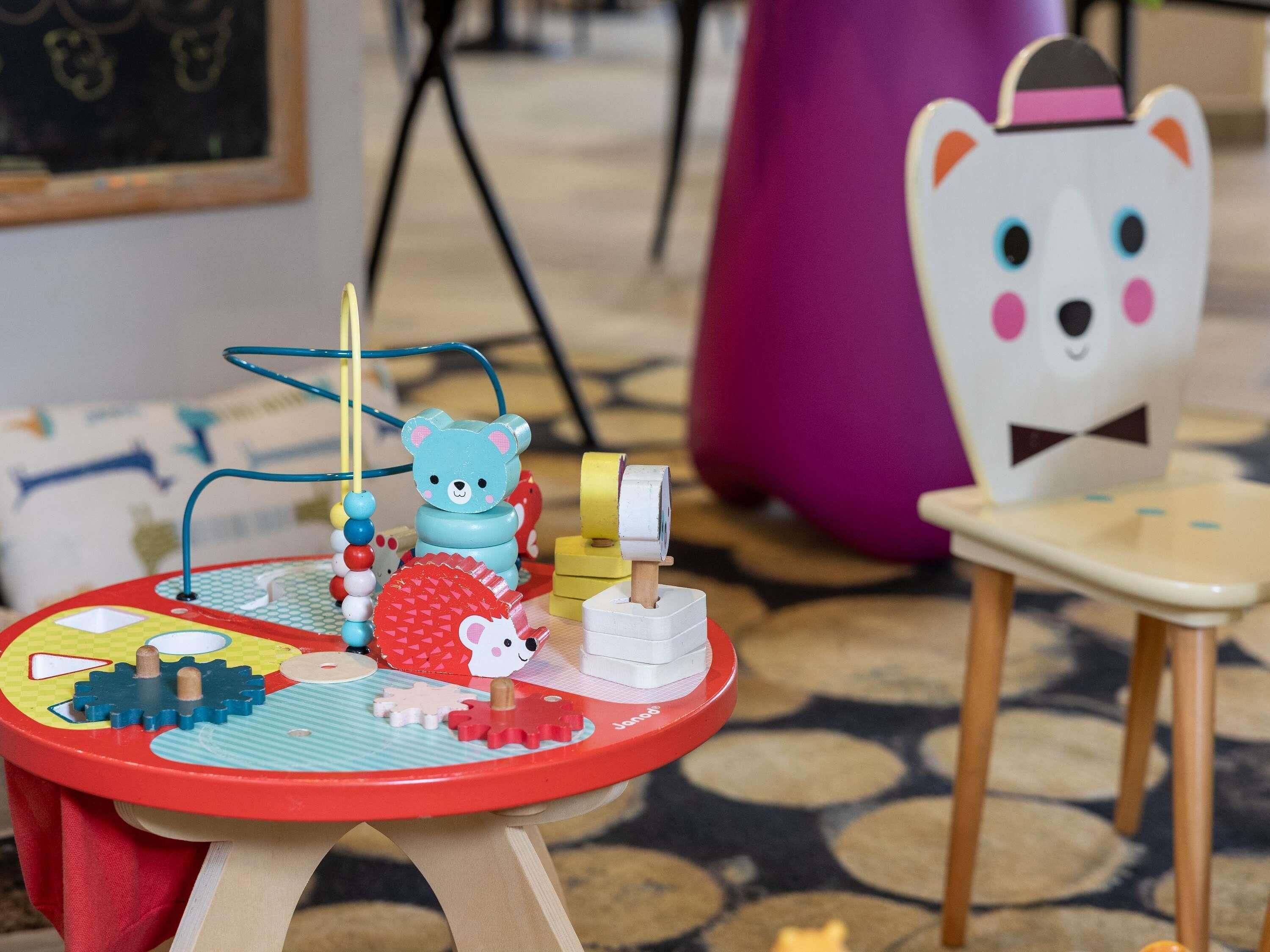 A children's play area with a table, a small chair, and various toys.