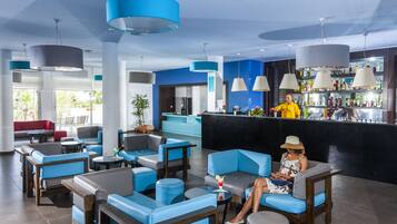 Een moderne lounge met blauwe en grijze zitplaatsen, een bar met een zwarte toonbank en een receptiebalie.