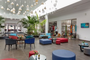 Un lobby amplio con mobiliario moderno, una zona de estar y una tienda con objetos de colores.