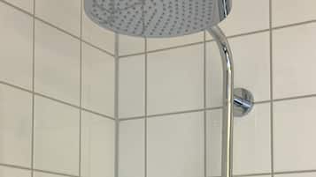 A corner shower with a round head and a smaller handheld showerhead, mounted on a chrome fixture against a tiled wall.