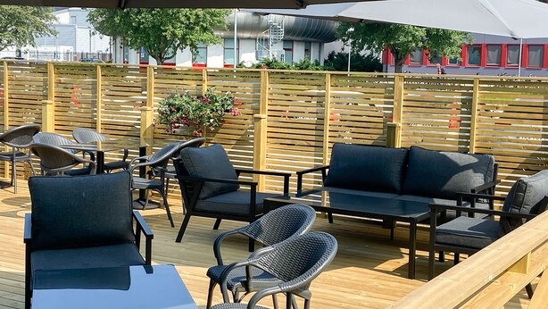Un espacio al aire libre con mobiliario de madera y vistas a la ciudad.
