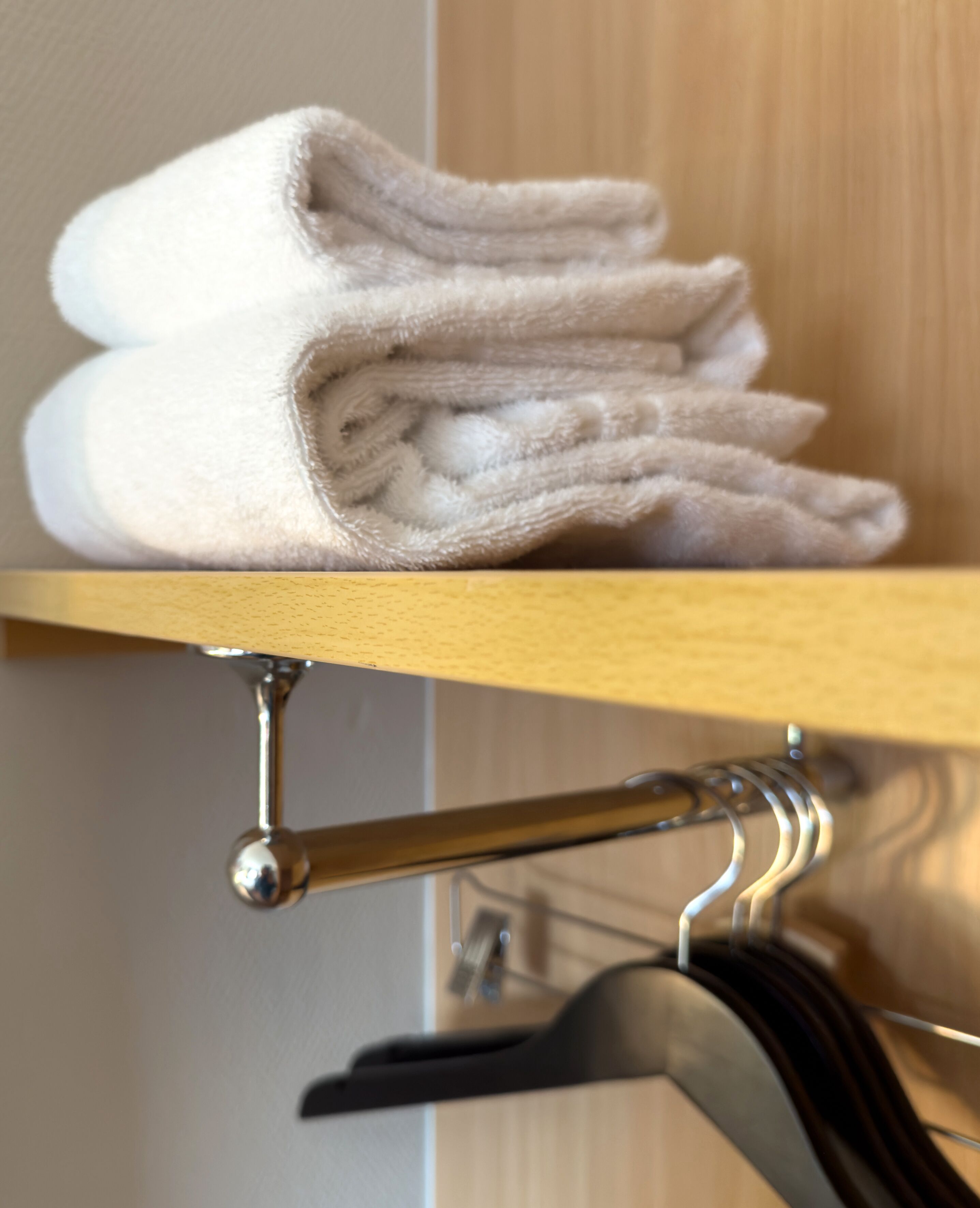 A stack of folded towels on a wooden shelf.