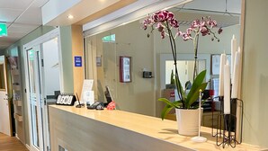 Una mesa de recepción con mostrador de madera, una planta en maceta y un cartel que indica el año 2020.