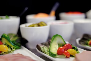 A variety of food items, including salads and dips, arranged on white plates.