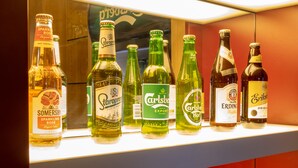 Variedad de bebidas embotelladas en estantes, incluyendo diferentes marcas y tipos de cerveza y sidra.
