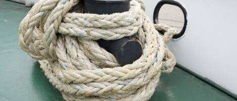 Una cuerda gruesa y enrollada atada alrededor de un objeto cilíndrico sobre un suelo verde.